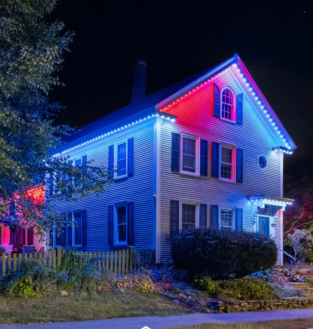Two-story home lit in red, white and blue with permanent trim lighting
