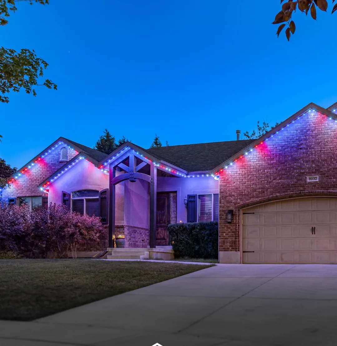 Brick home in red, white and blue permanent TrimLight lighting at dusk